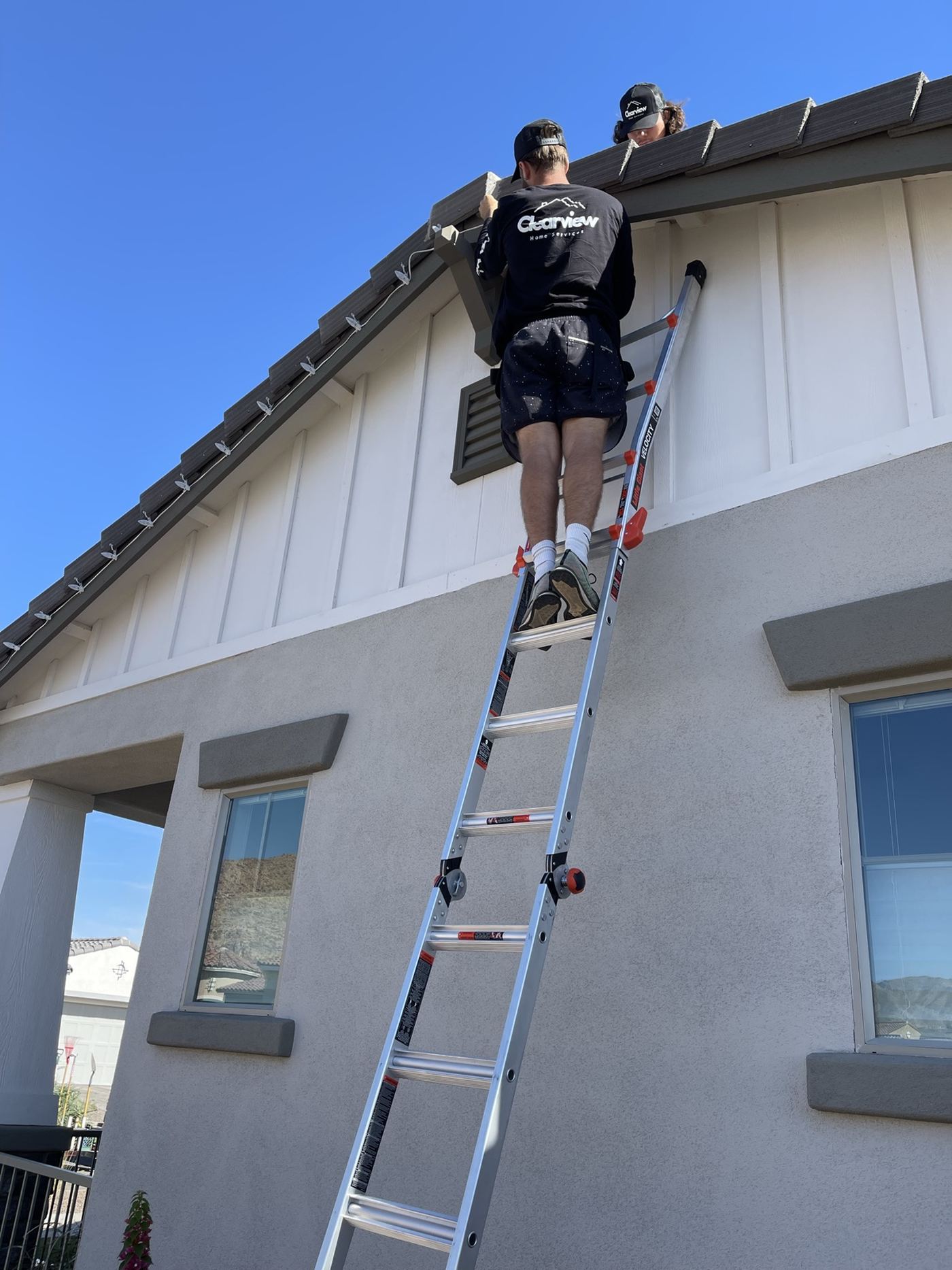 A Vero technician working the upper windows of a two-story home